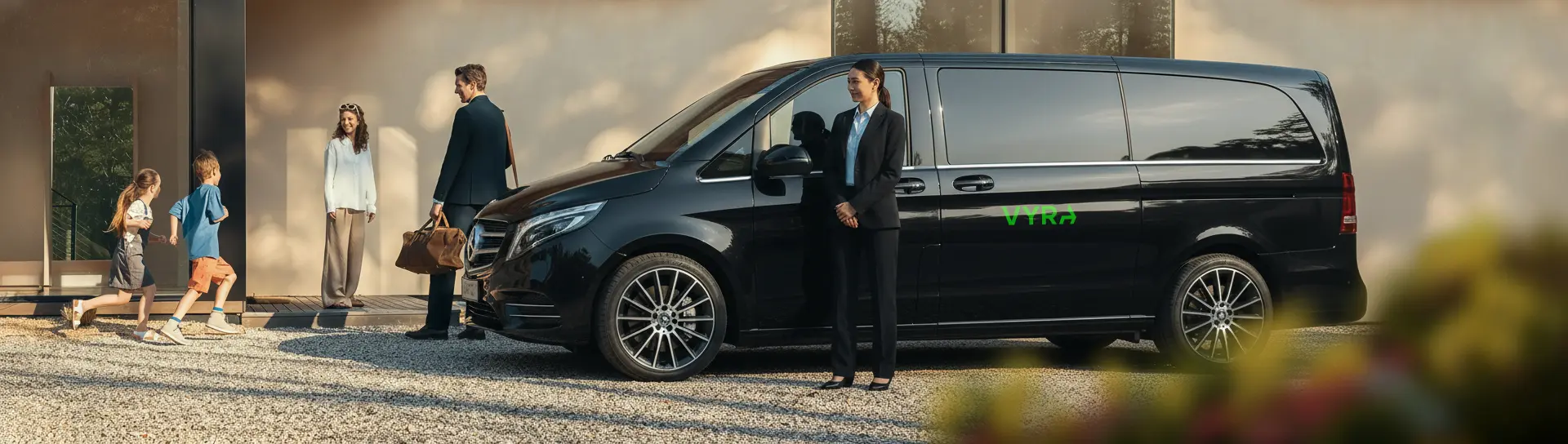 Black luxury van parked outside a modern house with a chauffeur ready to provide Marrakech airport transfer service to a family with children.